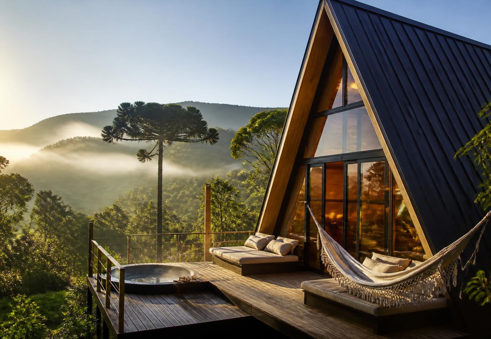 Chalé A-Frame com deck e rede, usado para hospedagem em meio à natureza